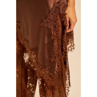Woman wearing a brown satin outfit with lace detail asymmetric top and lace pants