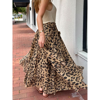 Person wearing a leopard print skirt outdoors on a sidewalk.