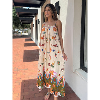 Woman wearing a colorful gypsy style bohemian sundress standing on a sidewalk.