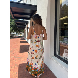 Woman wearing a colorful gypsy style bohemian sundress standing on a sidewalk.