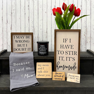 Decorative items including signs, a towel, and a vase with red tulips on a wooden surface.