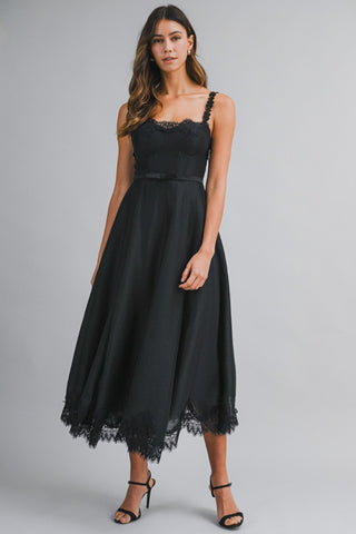 Woman wearing a black dress with lace details on a gray background