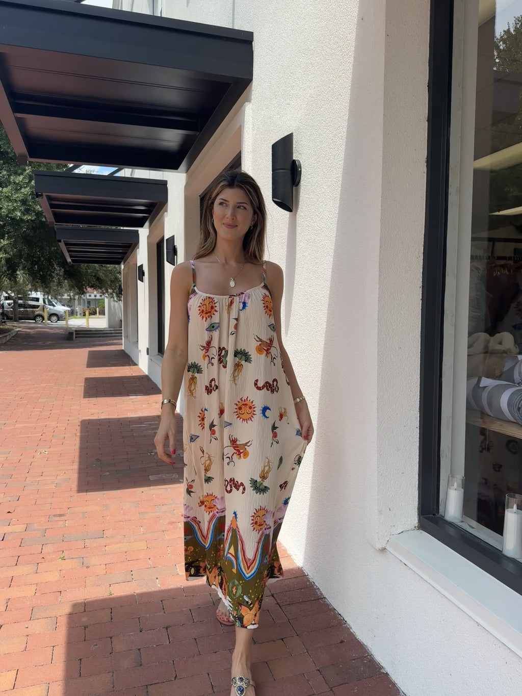 Woman wearing a colorful gypsy style bohemian sundress standing on a sidewalk.